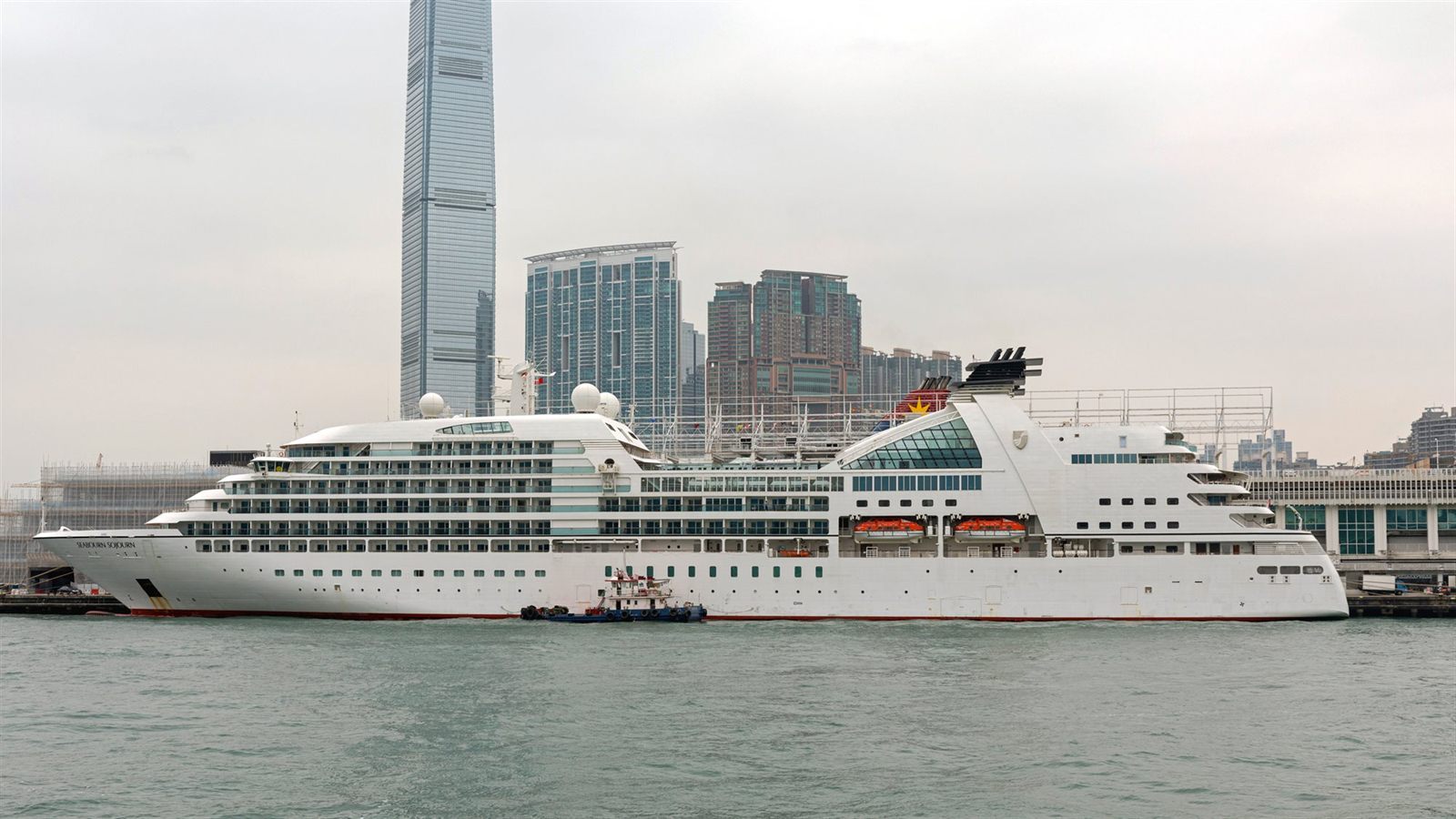 White cruise ship at the pier in Hong Kong with skyscrapers behind