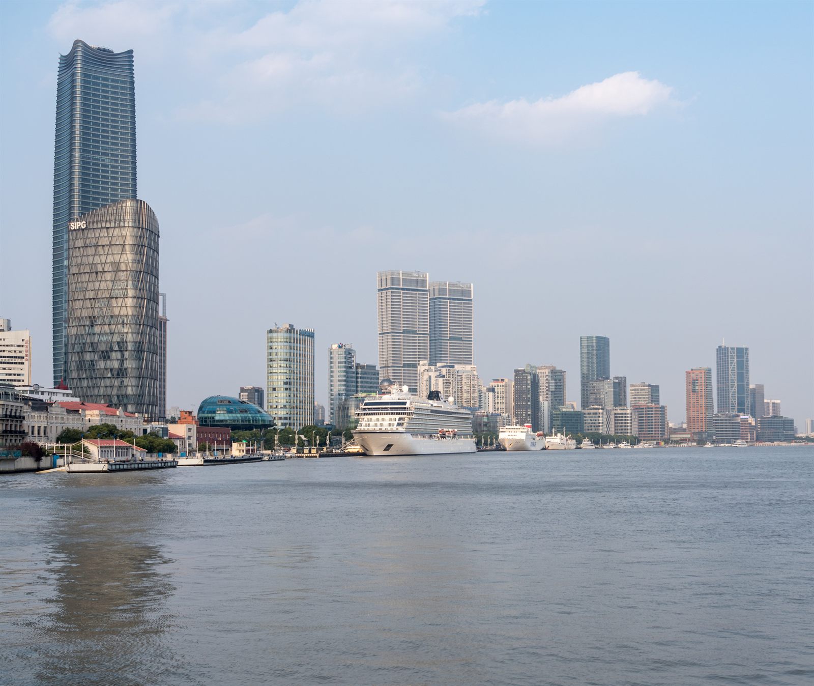 Cruise ship docked on the Huangpu River below Shanghai towers on a hazy day